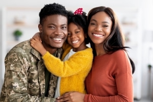 African-American military veteran smiling with wife and daughter