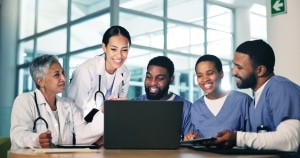 Medical professionals standing around a laptop